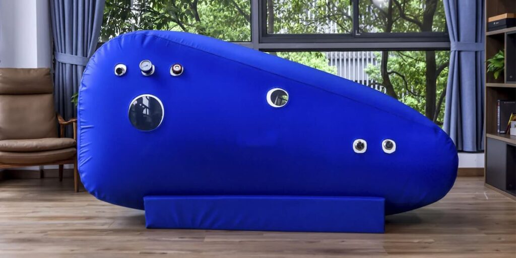 Sit Up Hyperbarix Oxygen Therapy Chamber in Blue situated in home room