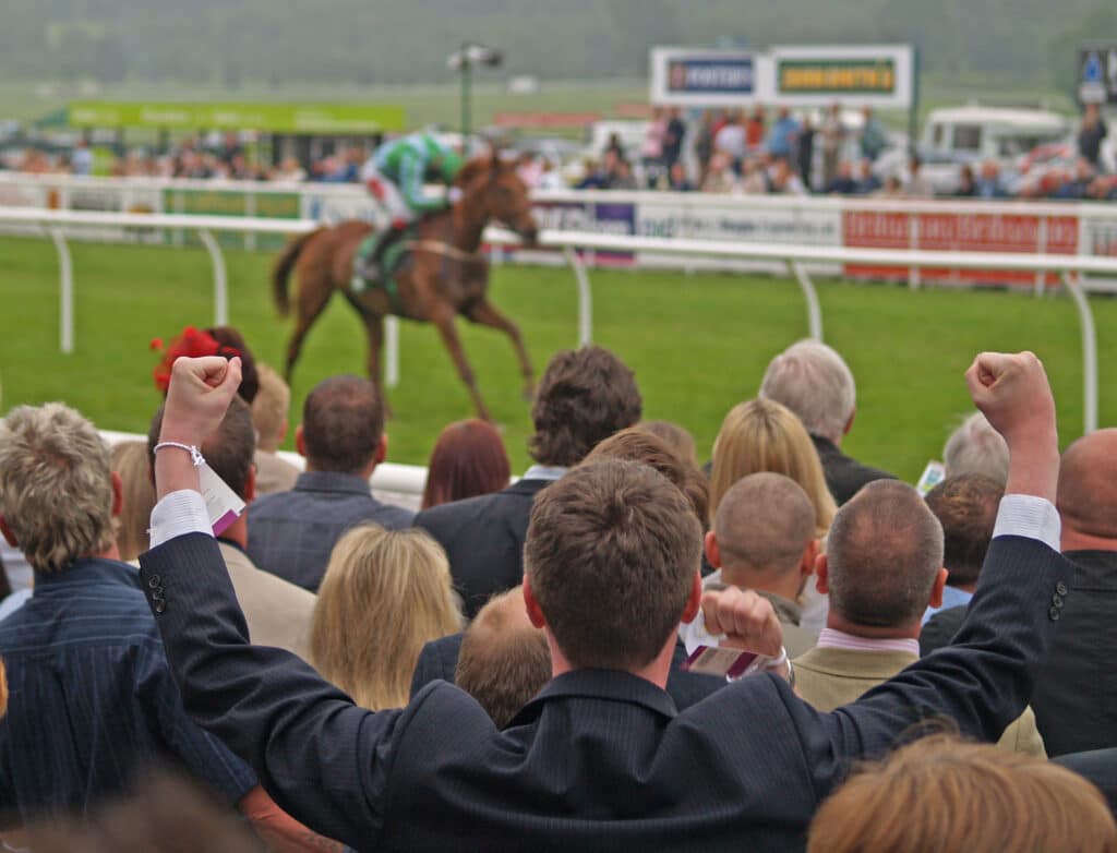 A man celebrates a win at the horse races.