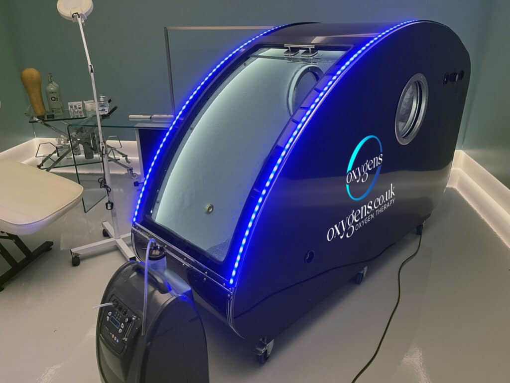 UKCA certified hyperbaric oxygen therapy chamber by Oxygens UK, shown in a clinical setting with advanced blue LED optimization and oxygen concentration system for 2.0 ATA recovery.