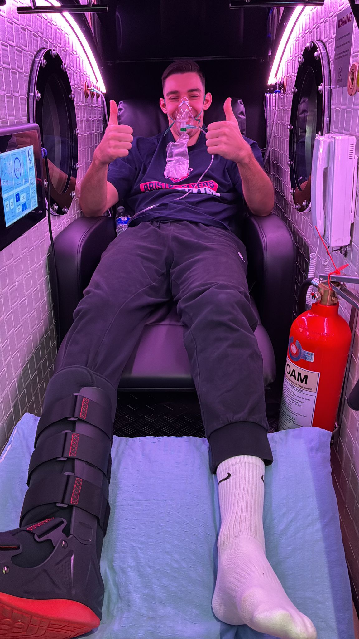 A visitor seated inside an Oxygens Winslet hard-sided hyperbaric chamber